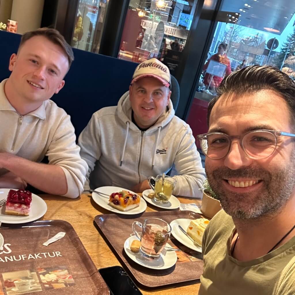 Drei lächelnde Personen beim Kaffee und Kuchen während einer Pause beim Crypton Event.