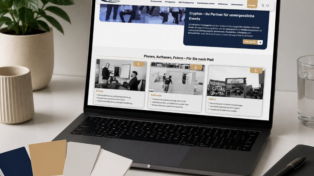 Laptop zeigt die Crypton-Event-Webseite mit drei Informationskarten, neben Farbmusterfächern auf einem Schreibtisch.