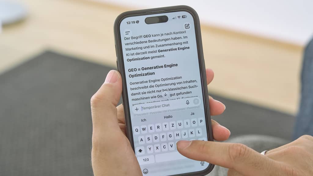 Smartphone zeigt Text zu „Generative Engine Optimization“, Finger tippt auf die Tastatur.