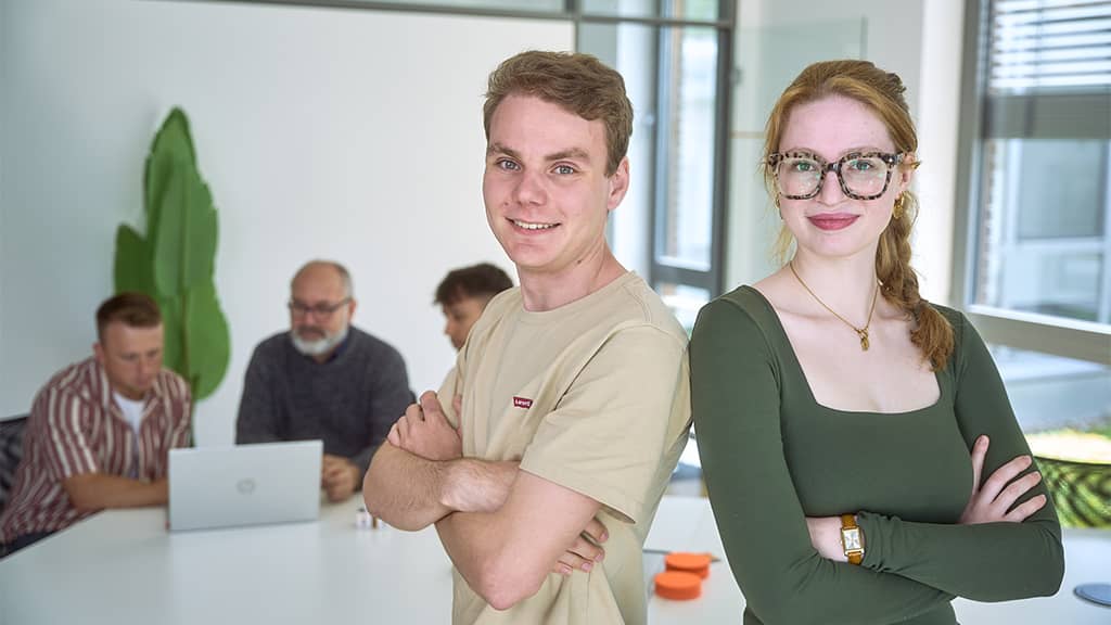 Zwei junge Mitarbeitende blicken zuversichtlich in die Kamera, symbolisch für Expertise und Erfolg in digitalen Werbekampagnen einer Google Ads Agentur.