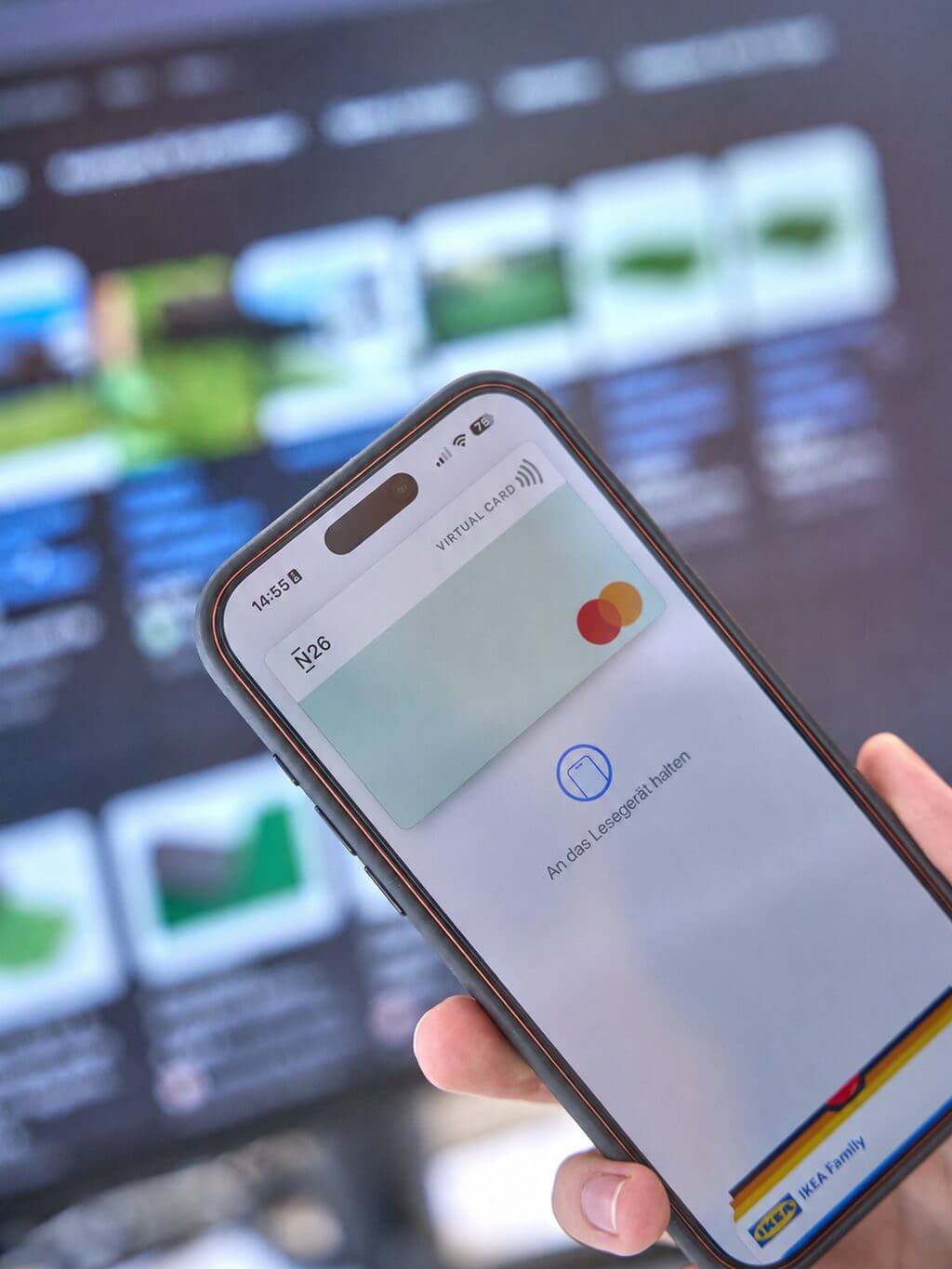 Smartphone zeigt eine digitale Kreditkarte im Wallet, bereit für kontaktloses Bezahlen vor unscharfem Bildschirm.