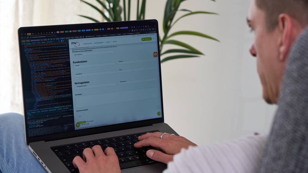 Eine Person sitzt am Laptop, auf dem links Quellcode und rechts ein Formular zu sehen sind.