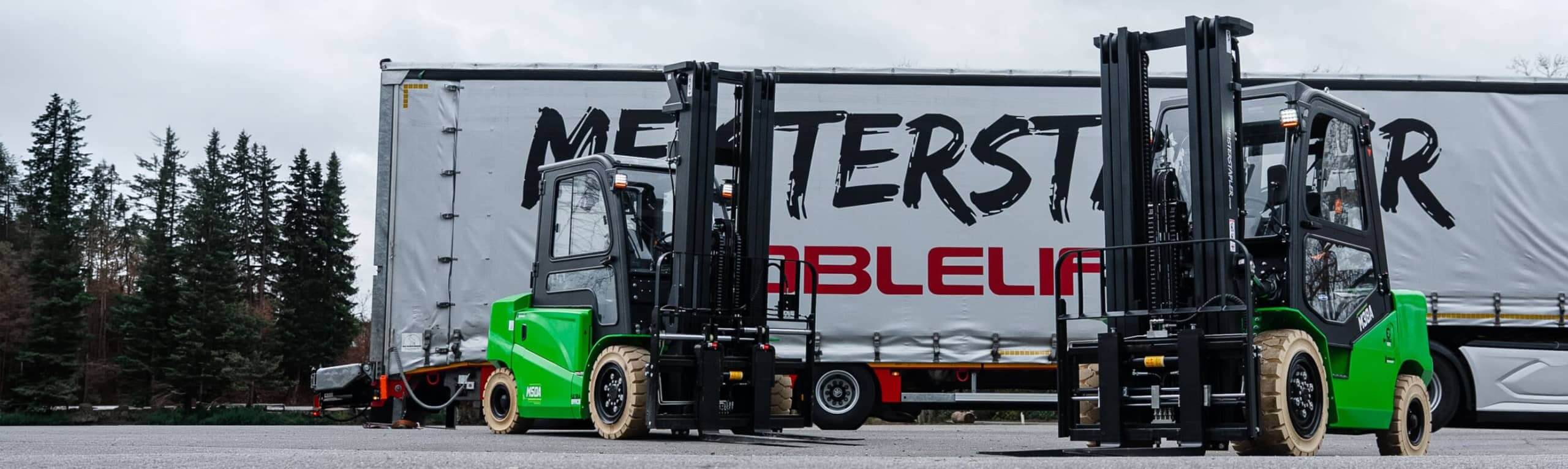 Zwei grüne Meisterstapler stehen nebeneinander vor einem Lkw-Anhänger mit Firmenbeschriftung, bereit für Be- und Entladung.