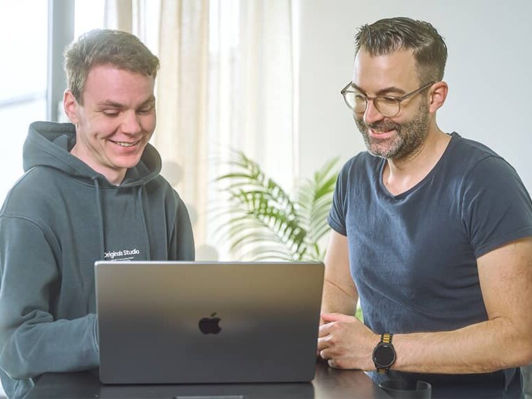 Zwei Personen arbeiten gemeinsam an einem Laptop während einer Schulung zur Suchmaschinenwerbung.
