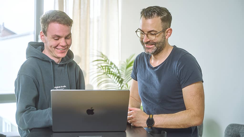 Zwei Personen arbeiten gemeinsam an einem Laptop während einer Schulung zur Suchmaschinenwerbung.
