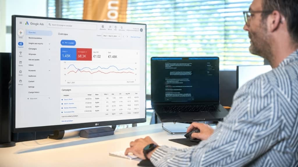 Arbeitsplatz mit Monitor, der Google Ads Kennzahlen und Diagramme zur Leistungsübersicht einer SEA-Kampagne zeigt.