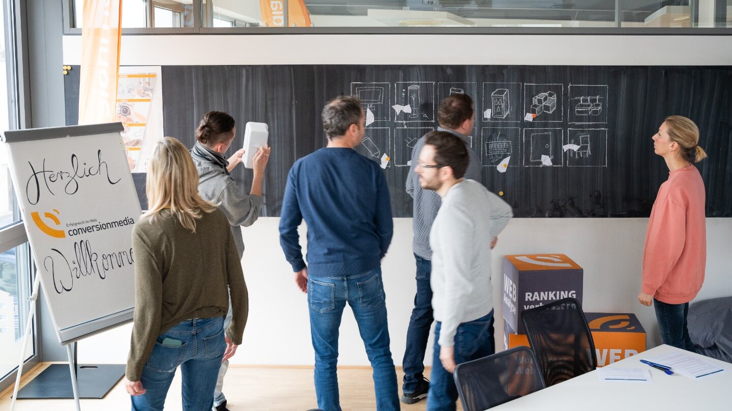 Kollegen lösen zusammen strategisch ein Puzzle bei einem Escape Room Event im Büro.